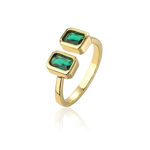 Gros plan d'une bague plaquée or avec des pierres de zircon vert sur fond blanc neutre