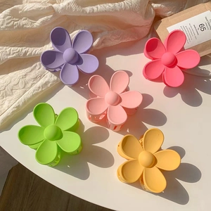 Detail of five colorful matte flower hair claws in purple, pink, green, and yellow hues