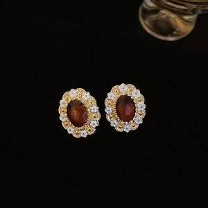 Macro shot of vintage gold stud earrings with oval amber stones and white floral details