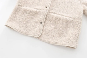 Detail of beige sherpa fleece jacket featuring textured fabric and hemline stitching