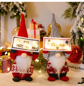 Detailed close-up of knitted Christmas gnomes featuring glowing LED HO HO HO signs