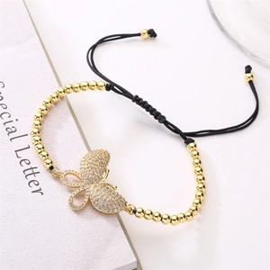 Detailed view of zircon butterfly charm with gold beads and black braided adjustable cord