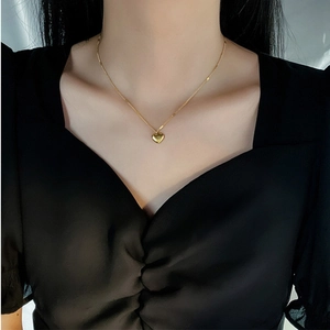 Detail of a minimalist gold-plated heart pendant necklace worn on a model's neck