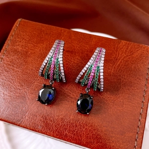 Detail of vintage oval pendant earrings with colorful zircons on brown leather base