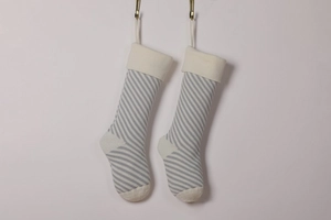 Detail of grey and white diagonal striped knitted Christmas stockings hanging on wall