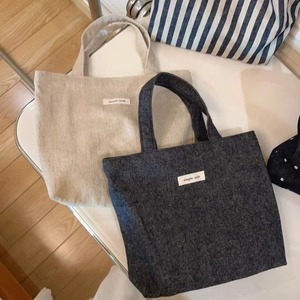 Detail view of canvas and denim tote bags with 'simple wish' label on a white chair