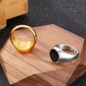 Close-up of minimalist gold and black oval signet rings for men on wood base