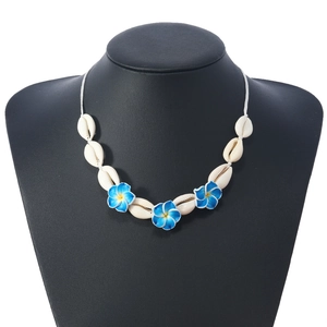 Collier style bohème avec coquillages blancs et fleurs bleues sur un mannequin noir