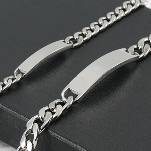 Polished stainless steel Cuban link ID bracelets for men on textured black surface