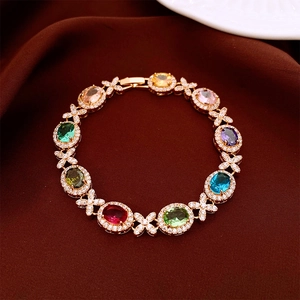 Dettaglio di un bracciale dorato con gemme ovali multicolori e accenti micro-pavé scintillanti
