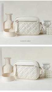 Macro shot of quilted diamond patterns and metal zipper detail on cream crossbody bag