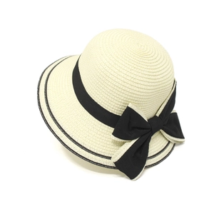 Detailed close-up of woven beige straw hat featuring elegant black ribbon with bow detail