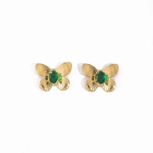 Detailed view of golden butterfly earrings with green stones and striped texture