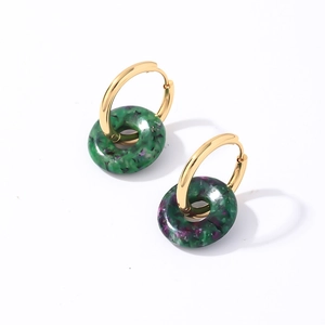 Détail de boucles d'oreilles créoles dorées avec pendentifs en pierre naturelle bicolore