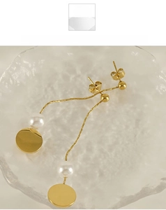 Close-up of 18K gold tassel earrings with pearls on elegant textured glass