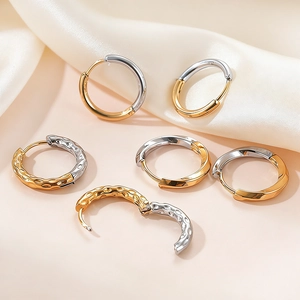 Polished gold and silver two-tone hoop earrings with hammered texture on silk fabric