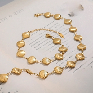 Parure collier et bracelet de cheville avec pendentif coquillage doré sur pages de livre