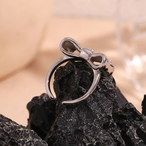 Detail of silver bow-shaped open ring placed on a textured dark volcanic stone surface