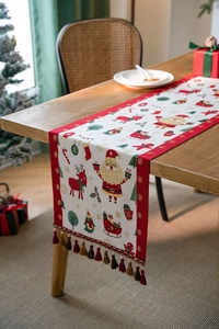Detail of Christmas table runner with festive deer patterns and red tassel edges
