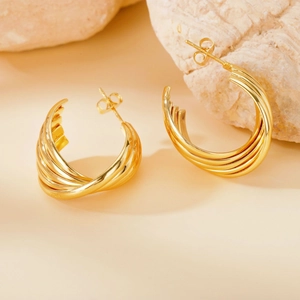 Detailed macro view of 316L gold earrings with spiral texture on a natural stone base