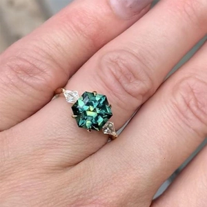 Elegant hexagon cut emerald ring in gold setting worn by model for luxury party look