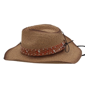 Detail of a brown woven cowboy hat featuring a red plaid band and silver rivets
