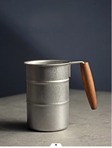 Detail of retro industrial stainless steel camping mug with smooth solid wood handle