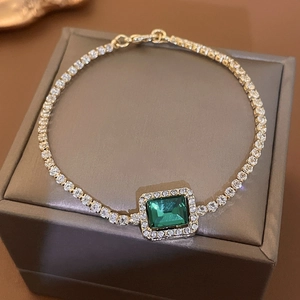 Macro detail of emerald-cut green zircon bracelet with shimmering diamond halo and tennis chain