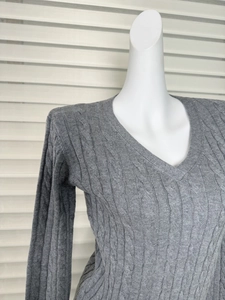 Close-up of gray cable knit sweater featuring a deep V-neck and intricate textured patterns