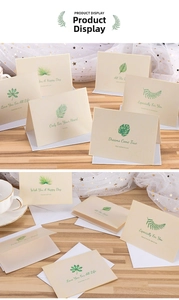 Detail of green leaf greeting card set on wooden desk with white envelope and envelopes