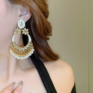 Close-up of bohemian hollow teardrop tassel earrings with white pearls and gold accents