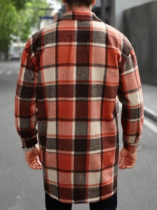 Back view of a men's long sleeve orange and brown plaid shirt jacket in a city street