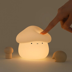 Rechargeable mushroom silicone night light with warm glow being pressed by hand