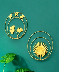 Detailed view of golden ginkgo and palm leaf metal wall art on a textured green background
