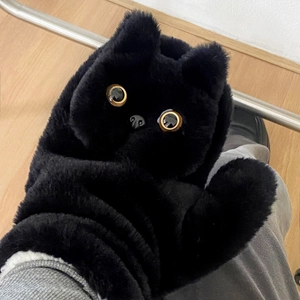 Close-up of black plush cat gloves showing soft faux fur and vivid golden glass eyes