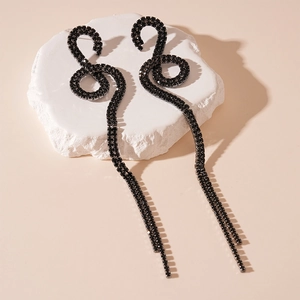 Detailed macro view of black rhinestone snake fringe earrings on a white stone background