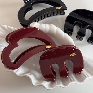 Close-up of heart-shaped hair claws in black and burgundy with gold Love plaque
