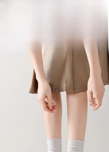 Close-up of brown skirt hem paired with white mesh lace silk socks for a layered look