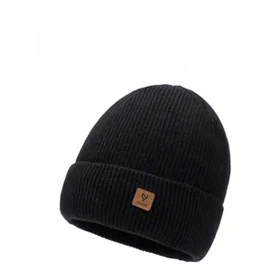 Detailed close-up of a black ribbed knit beanie with a brown leather logo patch