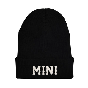 Detail of white plush MINI letter embroidery on a black knitted winter beanie hat