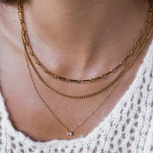 Gros plan sur collier triple rang doré avec chaîne trombone et pendentif zircon
