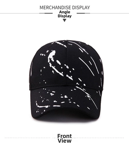 Detail of a black baseball cap with white graffiti ink splatter and premium stitching