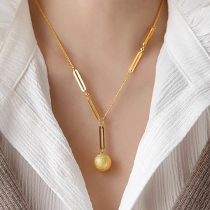 Elegant gold necklace with a matte round pendant and modern link chain on a female model