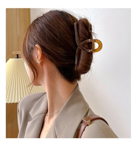 Détail d'une grande pince à cheveux ambrée sur modèle pour coiffure épaisse