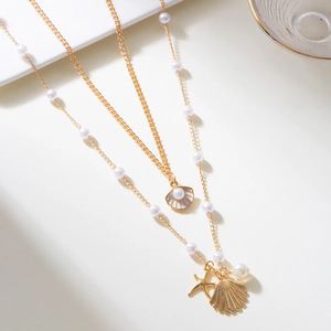 Detail of layered gold necklace featuring pearl shell pendants and a starfish charm