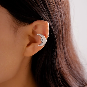 Detail of silver vintage crescent moon face ear cuff on a female model's ear