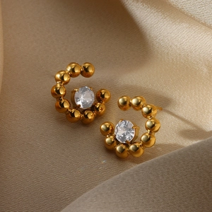 Close-up of golden pearl and zircon flower stud earrings on luxury champagne silk