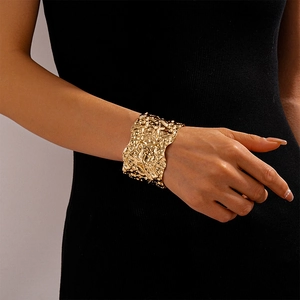 Detailed view of wide gold metal cuff bracelet with irregular wrinkled texture surface
