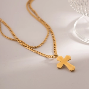 Detail of gold double-layer necklace with twisted chain and polished cross pendant
