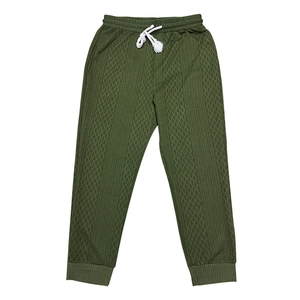 Detailed view of olive green knitted trousers featuring a unique diamond texture and drawstring